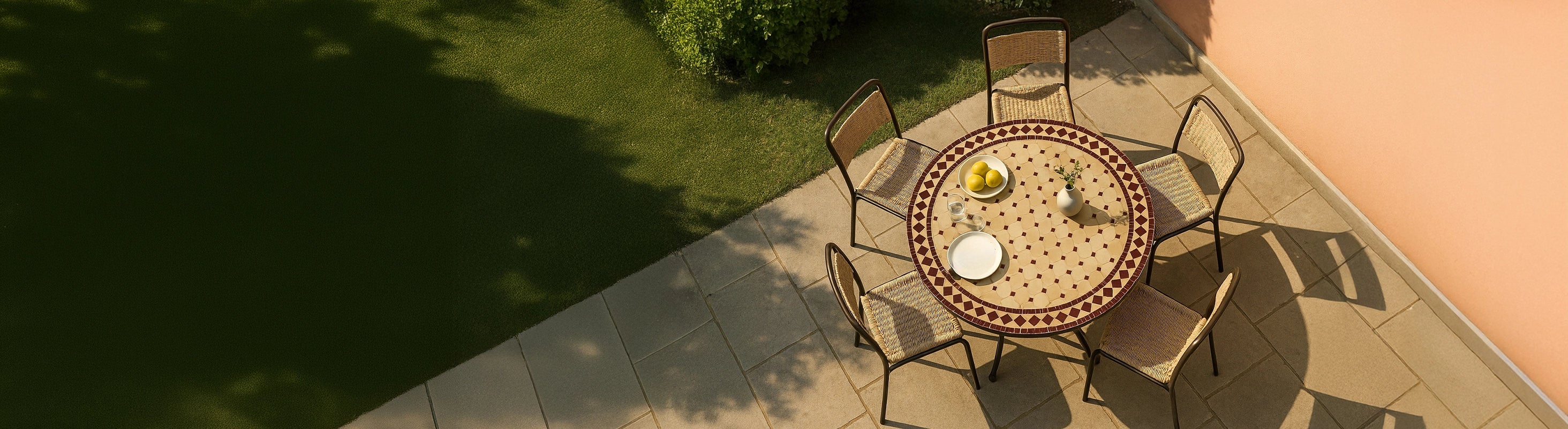 Mosaiktische Ø100 – Großer runder Mosaiktisch Ø100 cm mit Zellige-Fliesen und mehreren Stühlen auf Terrasse im Garten aus der Vogelperspektive mit warmem Sonnen