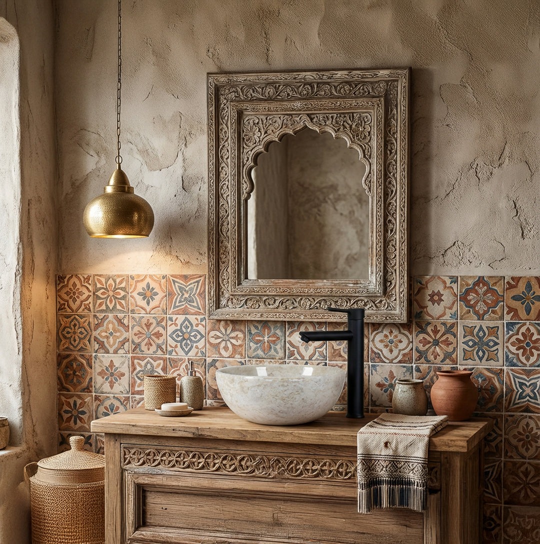 Rundes Naturstein-Waschbecken als Aufsatz auf Holzwaschtisch mit schwarzer Armatur vor gemusterten Fliesen im orientalischen Badambiente