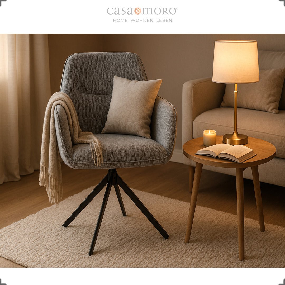 360° drehbarer Polsterstuhl mit Armlehnen in Grau, gemütlich arrangiert neben Beistelltisch, Lampe und Sofa in modernem Wohnzimmer 